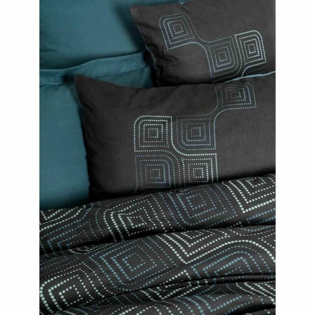 Bett mit dunkelgrauer Bettwäsche, Kissen mit geometrischem Design und schlichtem Hintergrund.