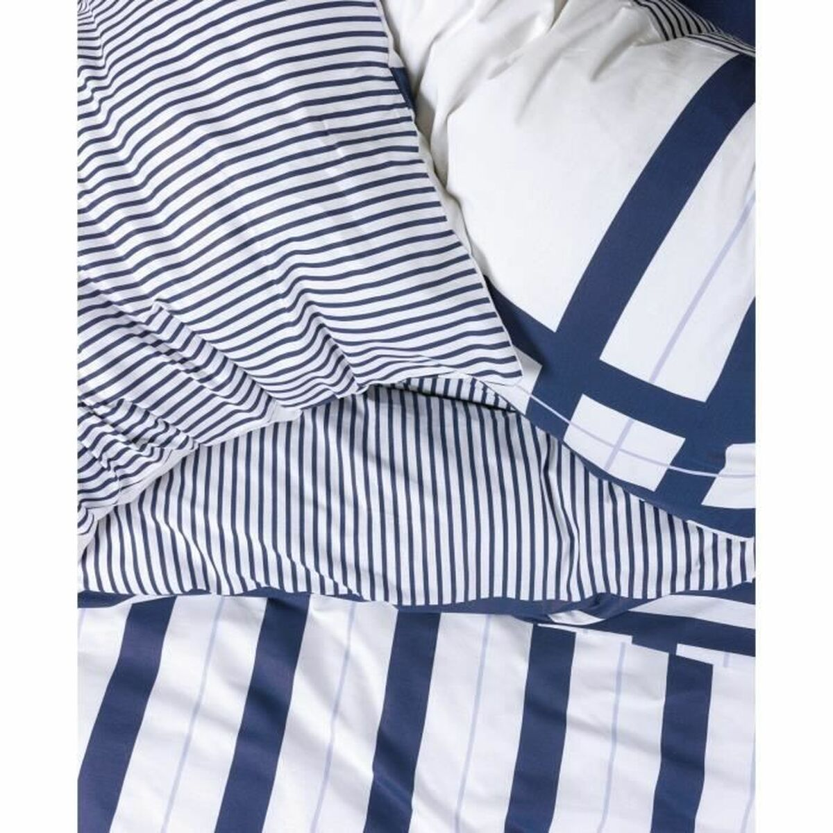 Draufsicht auf ein Bett mit weiß-blau gestreiftem Bettbezug und Kissenbezügen.