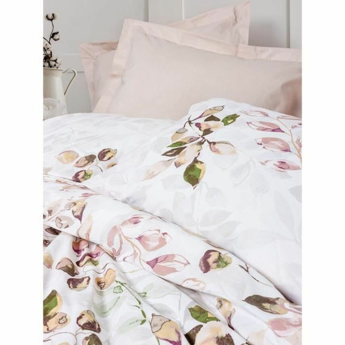 Bett mit weißer Blumendruck-Bettwäsche und rosa Kissen, eine weiße Wand und eine Vase mit Blumen.
