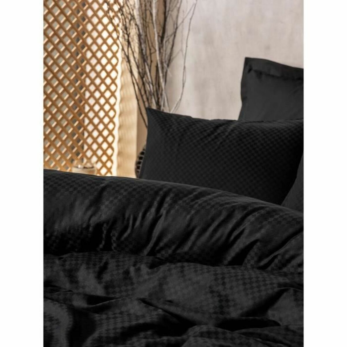 Nahaufnahme eines schwarzen Bettsets mit gemustertem Bettbezug und Kissen. Das Bett steht in einem Raum mit Holzwand.