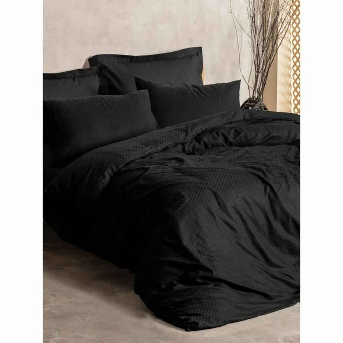 Bett mit schwarz karierter Bettwäsche und Kissen, mit neutralem Hintergrund und einem Zweig.