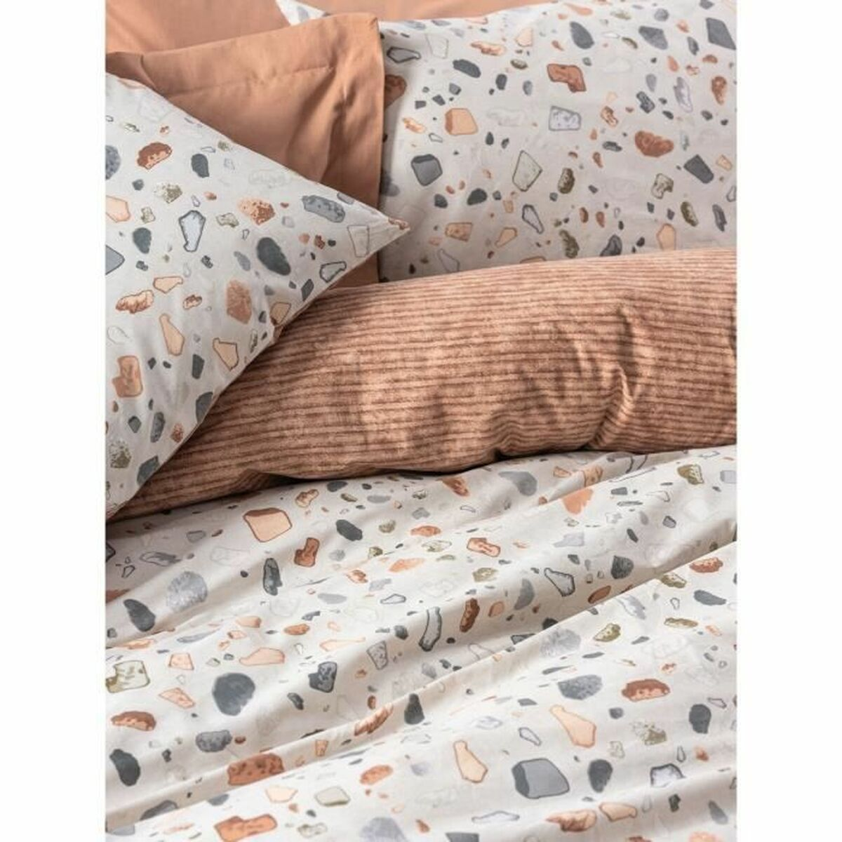 Nahaufnahme eines Bettsets mit weißer und gemusterter Bettdecke und Kissen. Das Bett vor weißem Hintergrund.
