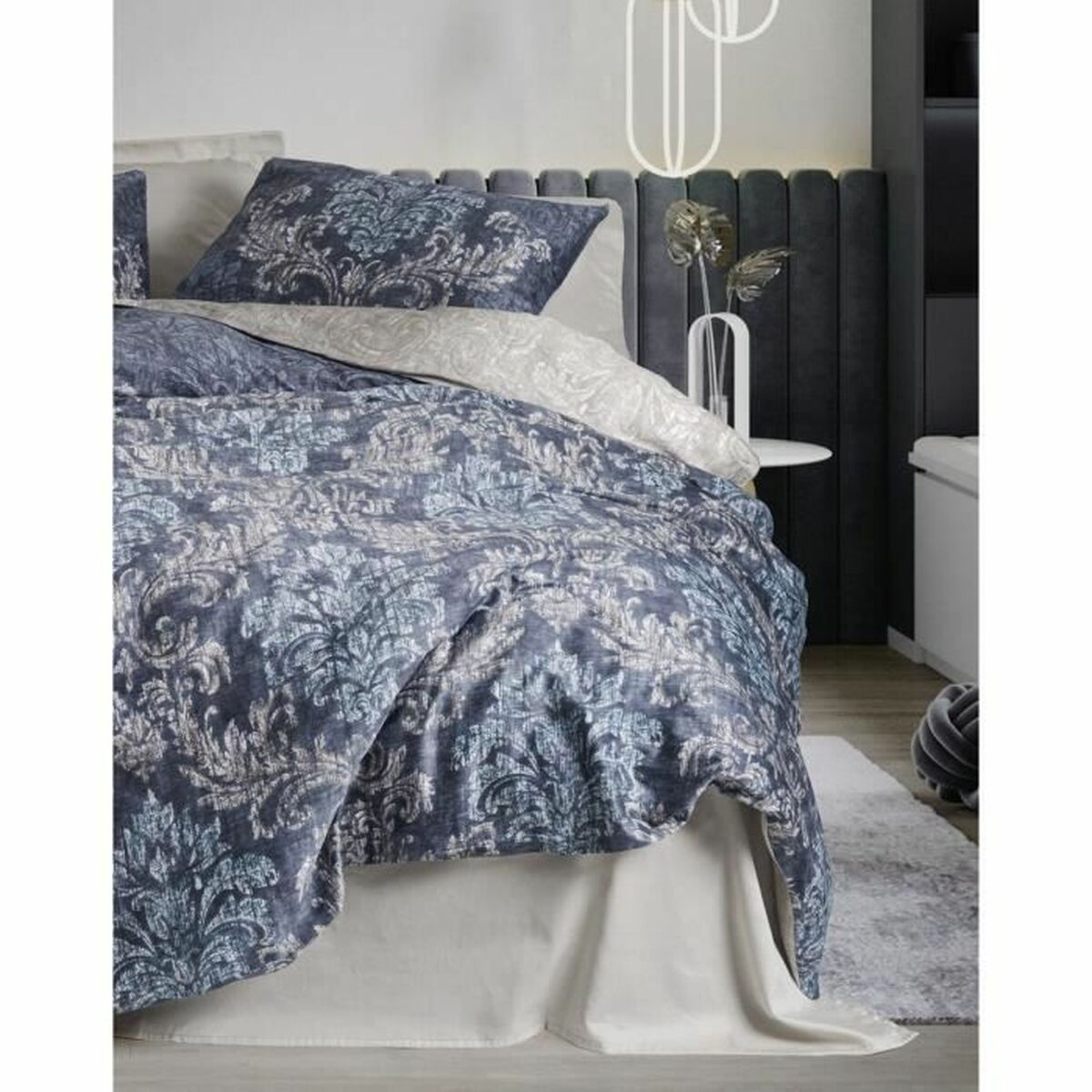Schlafzimmer mit gemusterter Bettdecke und Kissen.