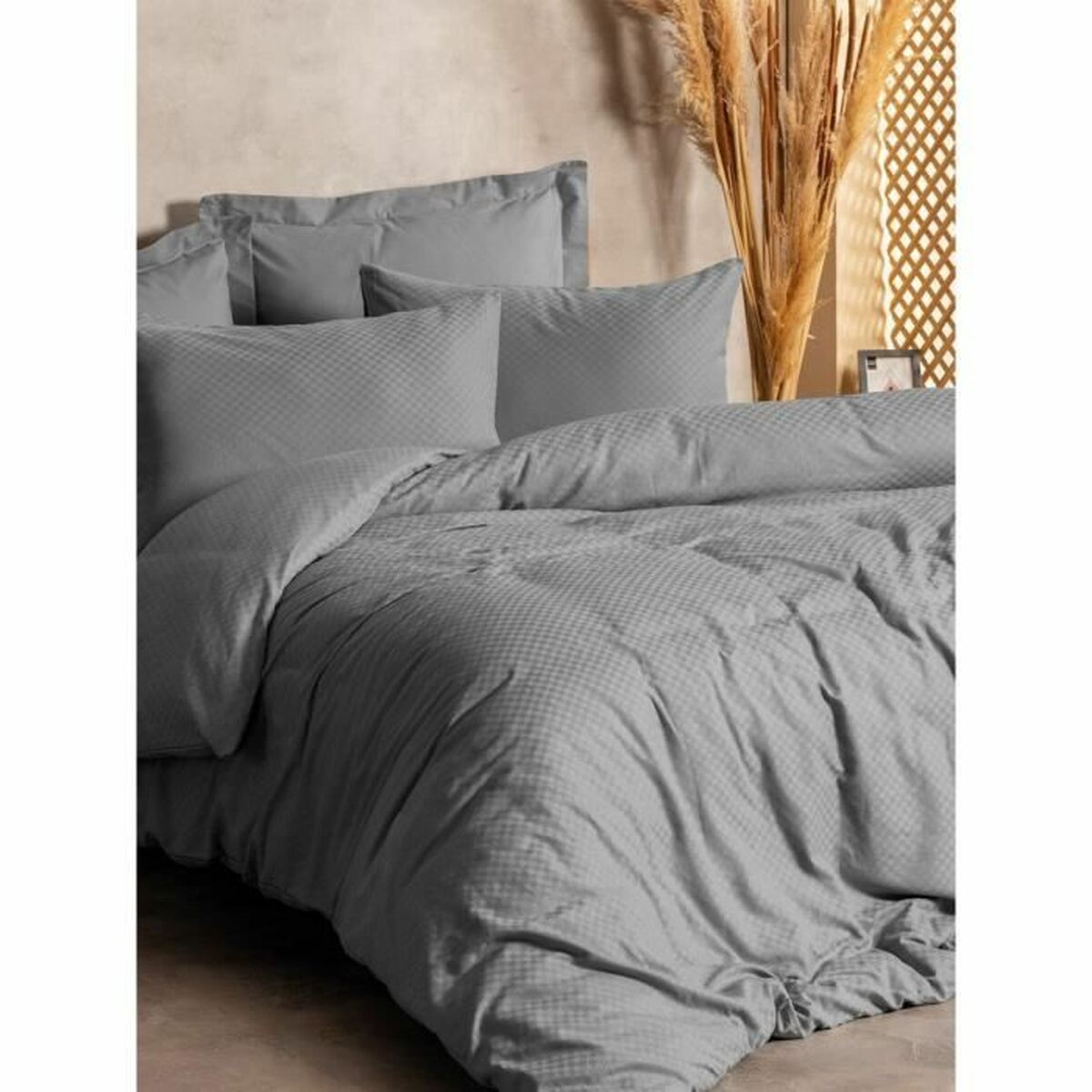 Graues Bettset mit strukturiertem Bettbezug und Kissen. Das Bett in einem Raum mit Holzwand und Deko.
