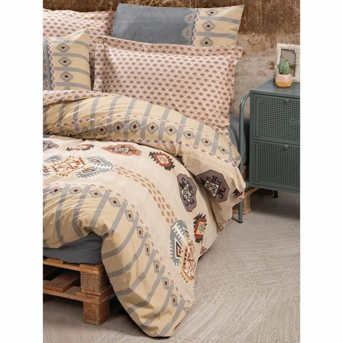 Beiges Bettwäsche-Set mit geometrischen Mustern auf einem Bett aus Holzpaletten. Rechts ist ein teal-farbener Beistelltisch.