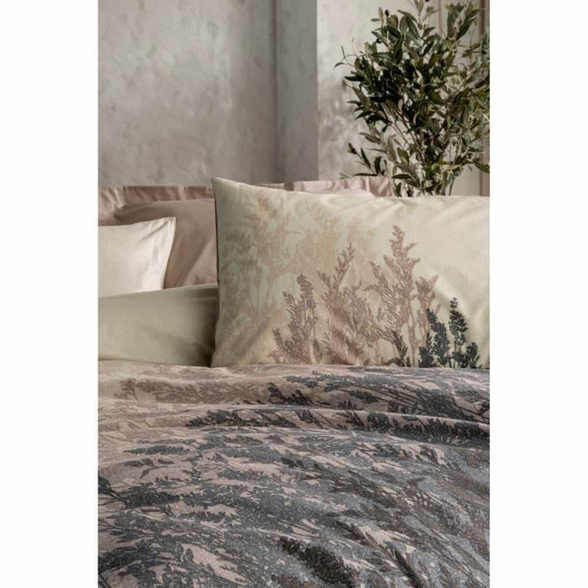 Bett mit floral gemusterter Bettwäsche und Kissen. Eine Pflanze in einem Topf befindet sich auf der rechten Seite.