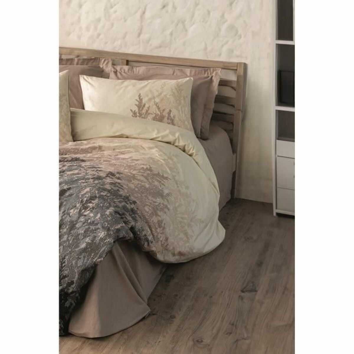 Bett mit gemusterter Bettwäsche. Die Wand ist strukturiert mit einer neutralen Farbpalette. Der Boden ist aus Holz.