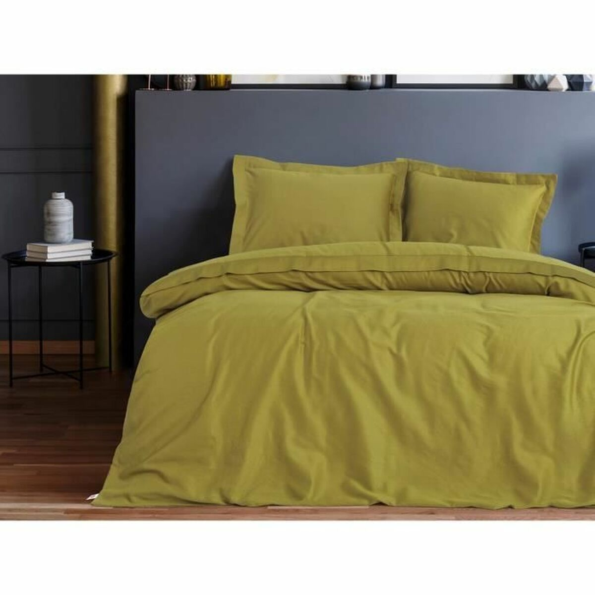 Bettwäsche-Set mit olivgrünen Laken, Kissen und Bettdecke. Das Bett ist gemacht und vor dunklem Hintergrund platziert.