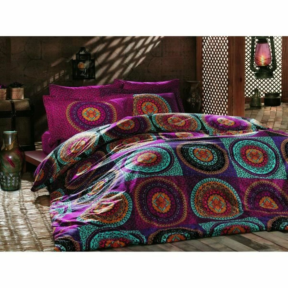 Bett mit lila Bettwäsche. Kissen und eine Steppdecke mit Mandalamuster. Holzboden und Wand.