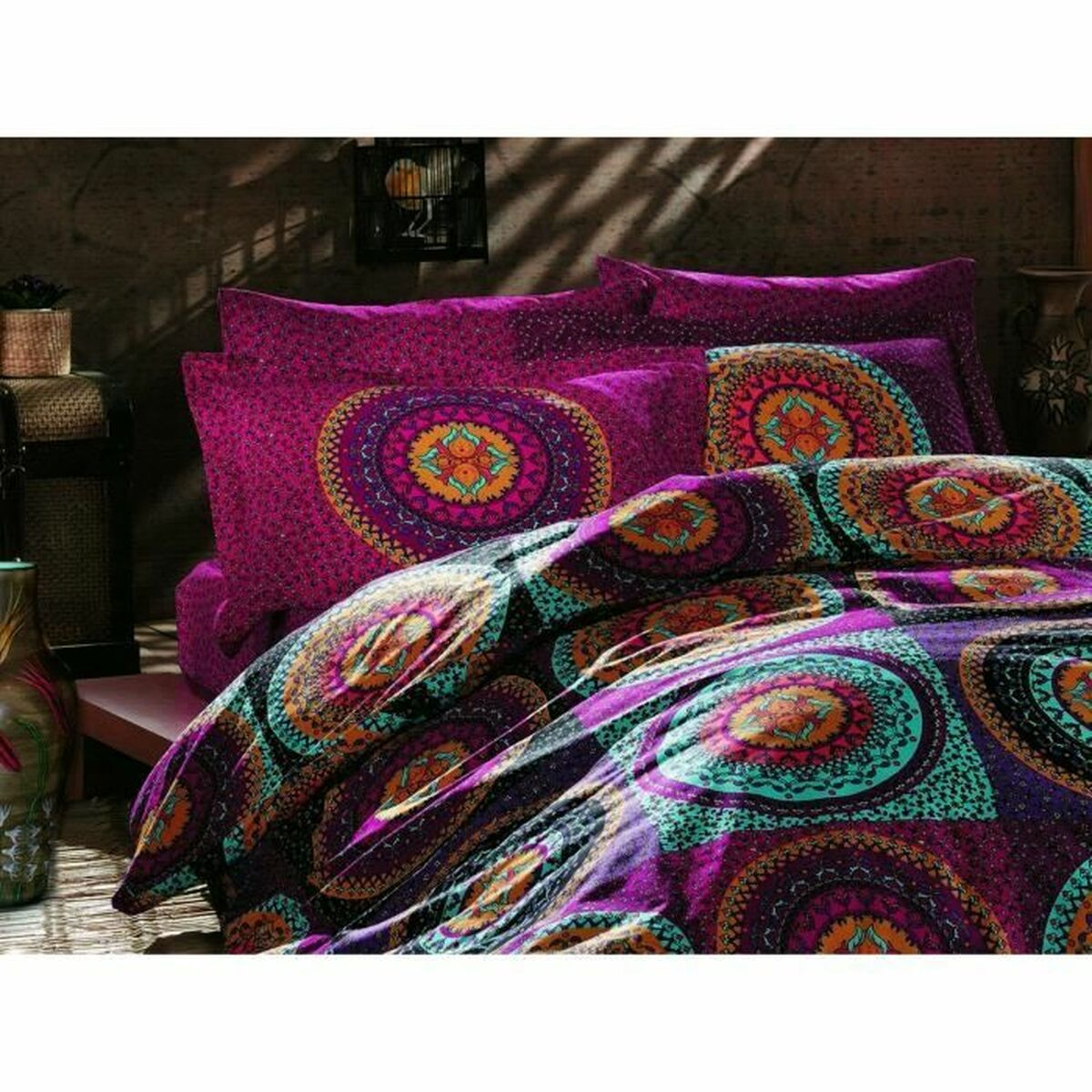 Bett mit lila Bettwäsche. Kissen und eine Steppdecke mit Mandalamuster. Holzboden und Wand.