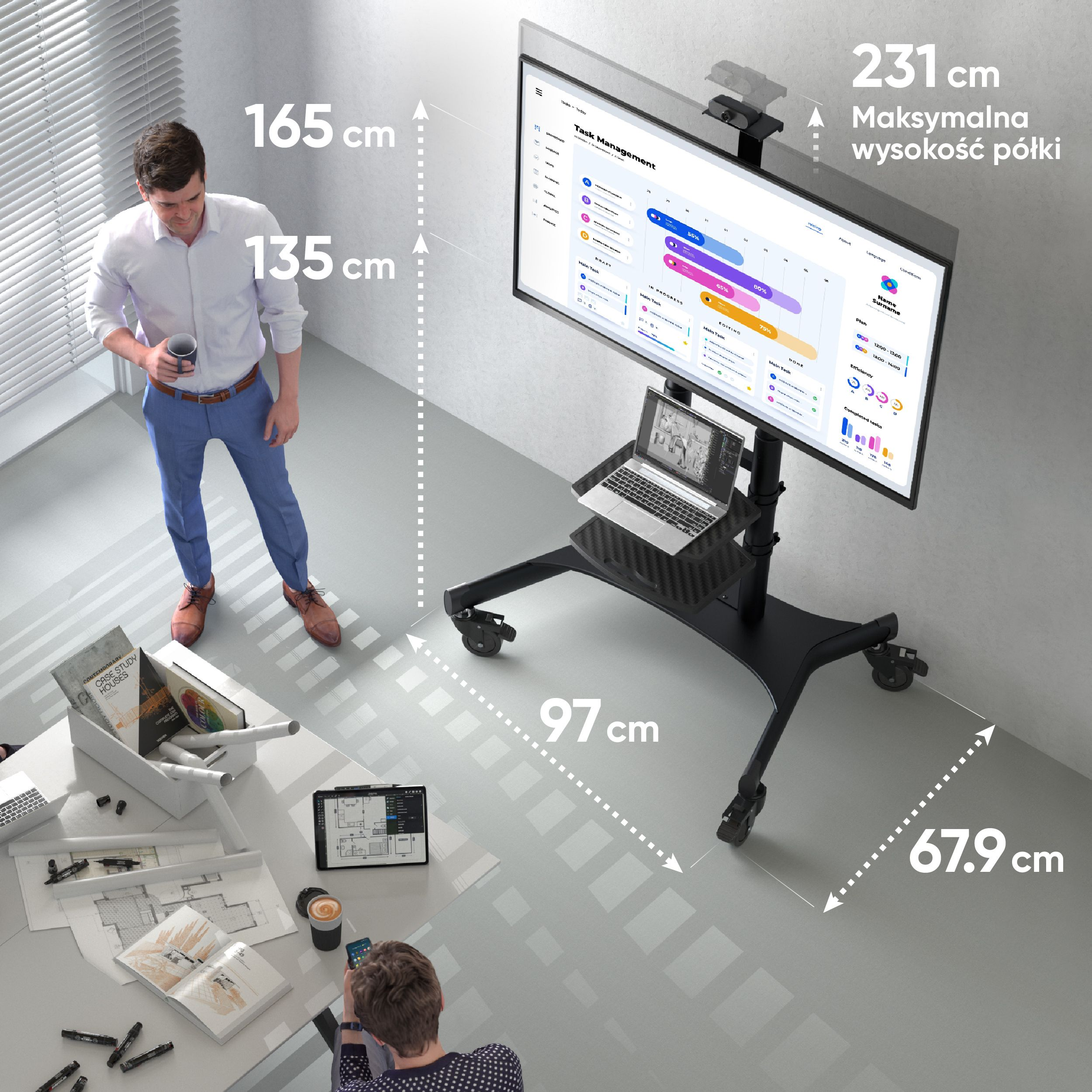 Mężczyzna stoi obok telewizora na stojaku. Laptop znajduje się na półce pod ekranem. Pokazano wymiary.