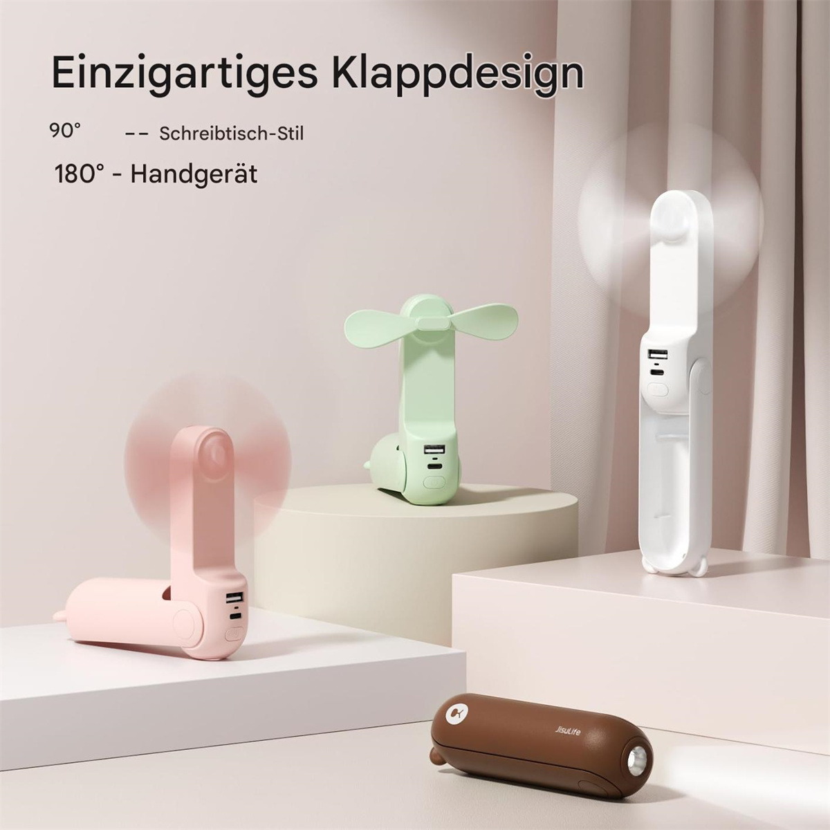 Drei kleine Ventilatoren in verschiedenen Farben: rosa, grün und weiß. Einer ist zusammengeklappt. Einer steht aufrecht. Einer ist offen und dreht sich.