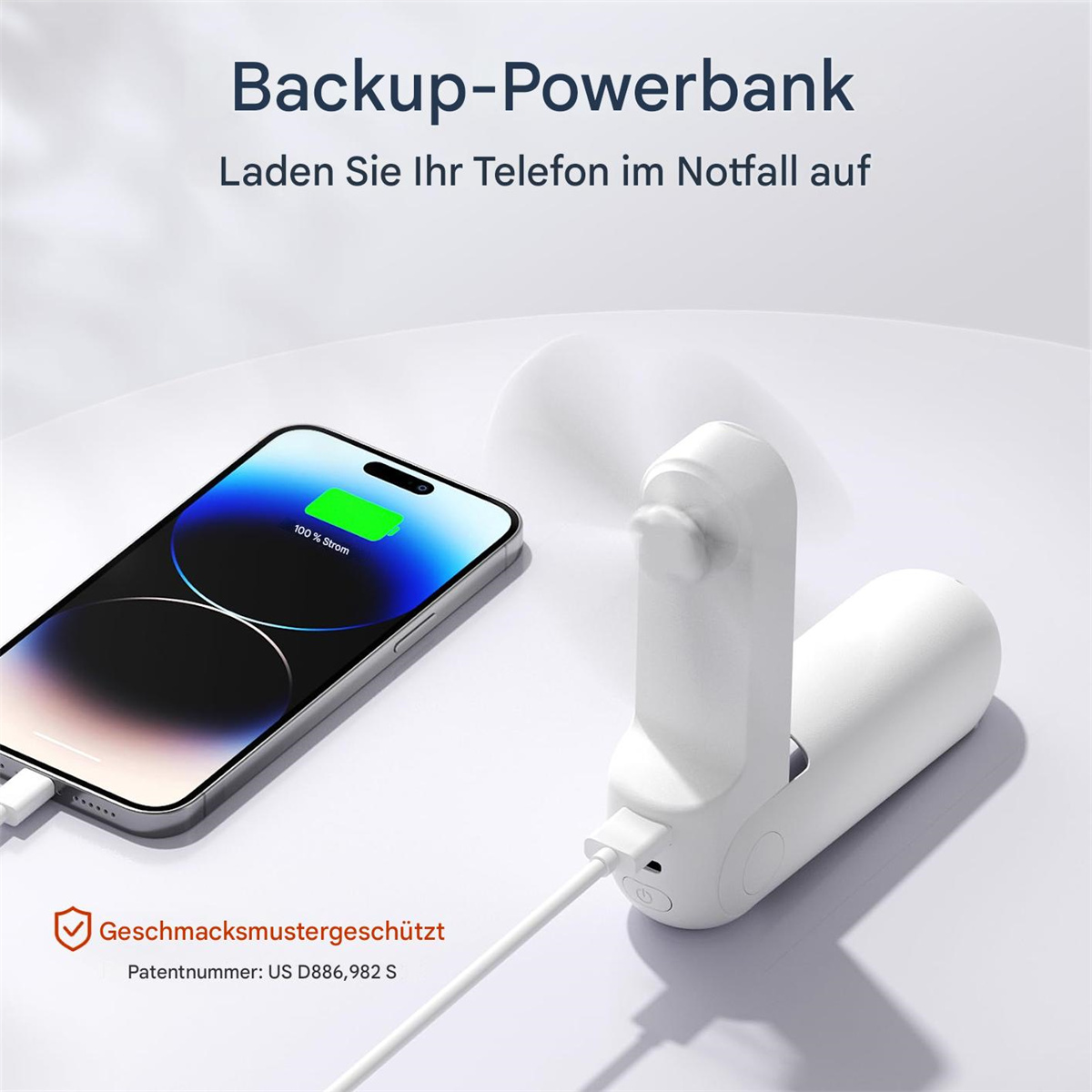 Ein weißer tragbarer Ventilator lädt ein Telefon auf. Das Telefon zeigt 100 % Ladung an. Der Hintergrund ist eine helle Oberfläche.