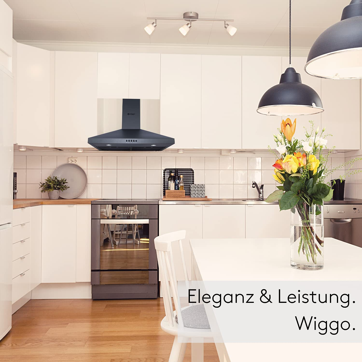 Eine moderne Küche mit weißen Schränken, einer schwarzen Dunstabzugshaube, einem Tisch und einer Blumenvase. Text: 'Elegance & Leistung. Wiggo.'