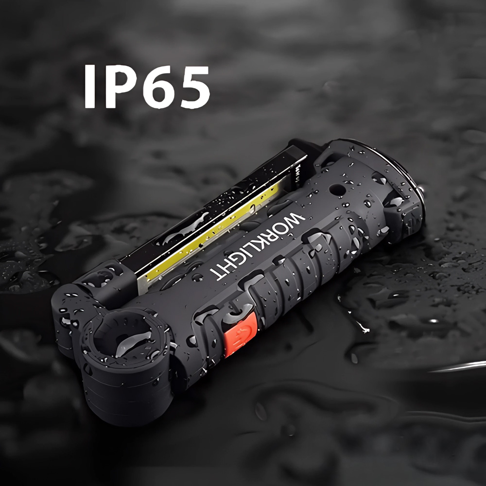 Luce da lavoro nera con testo 'WORKLIGHT' ed etichetta 'IP65'. Gocce d'acqua coprono la superficie. Pulsante rosso visibile.