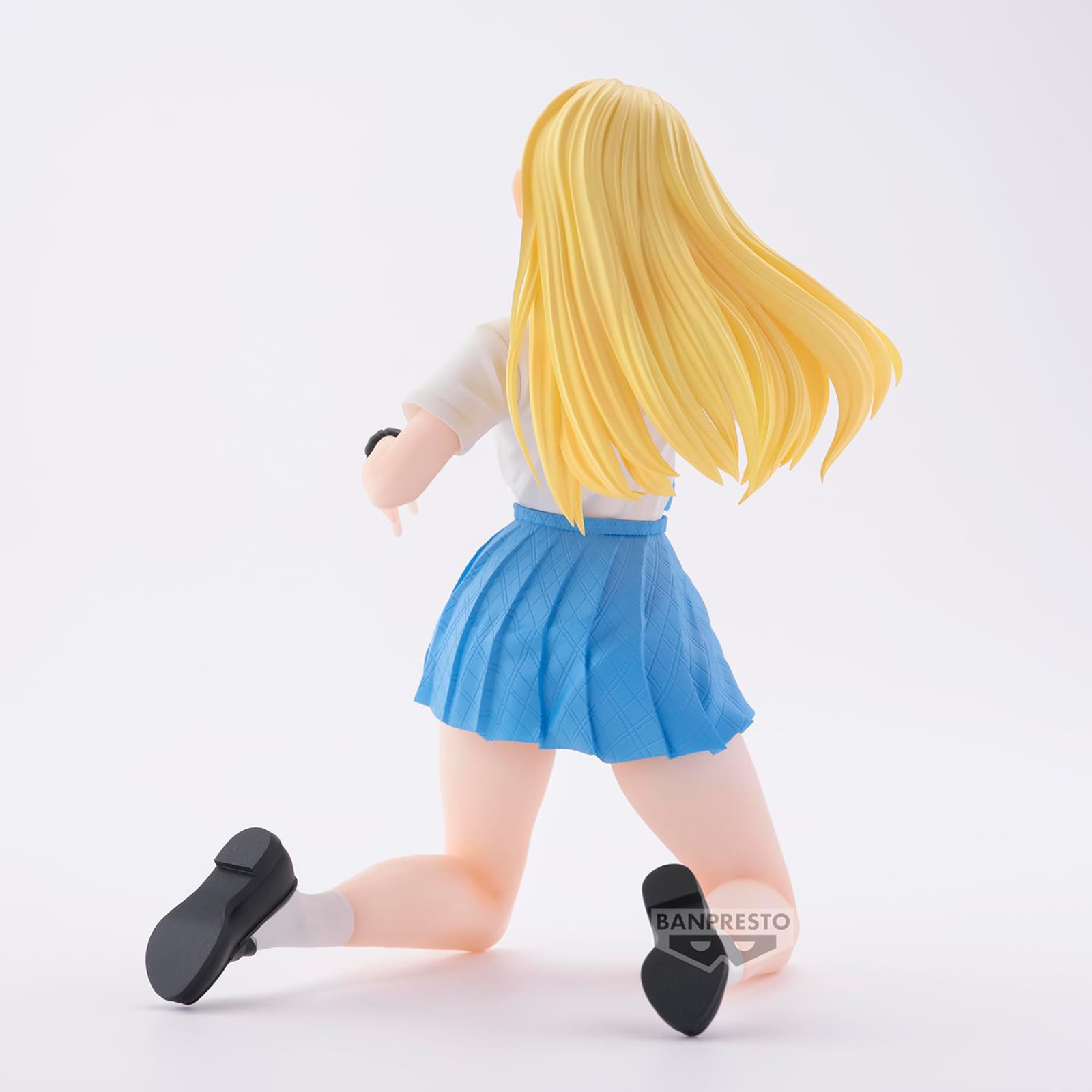 Figura anime de una chica rubia en uniforme escolar, arrodillada, vista trasera.