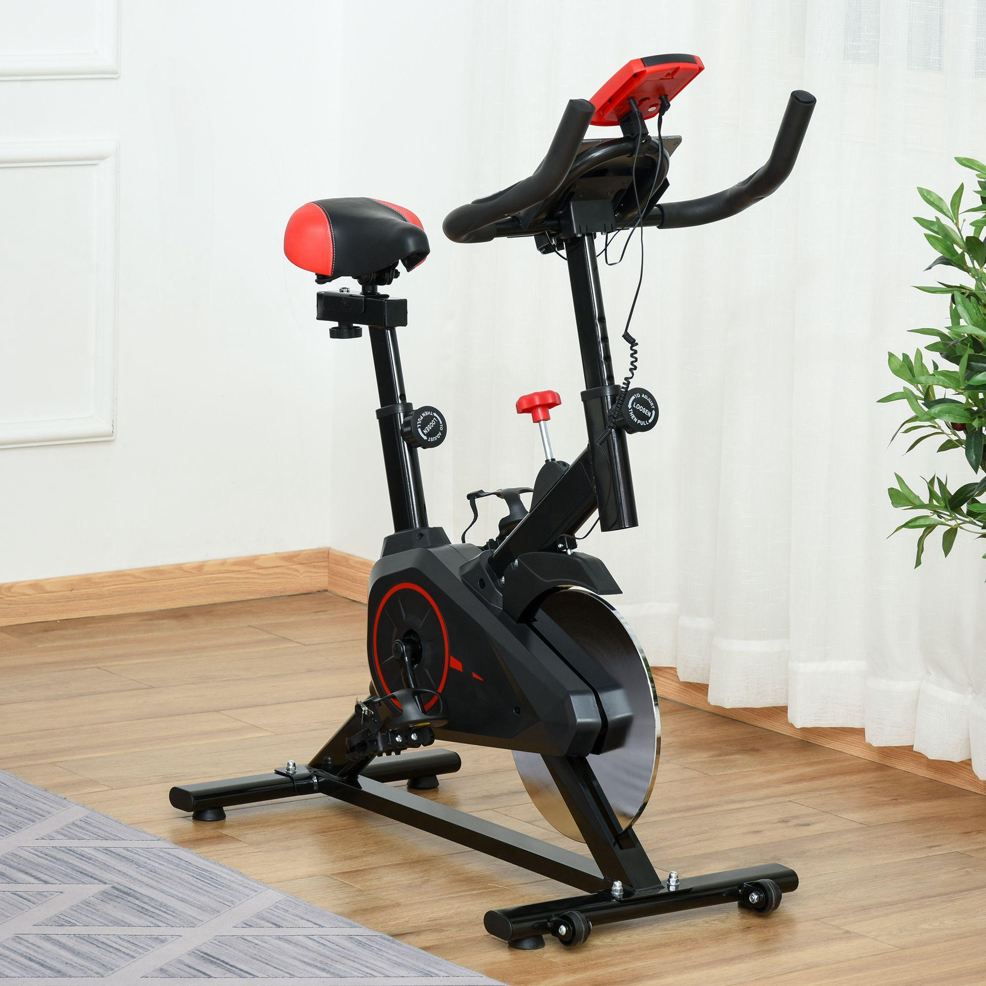 Ein Indoor-Heimtrainer. Es hat einen schwarzen Rahmen mit roten Akzenten und steht auf Holzboden.
