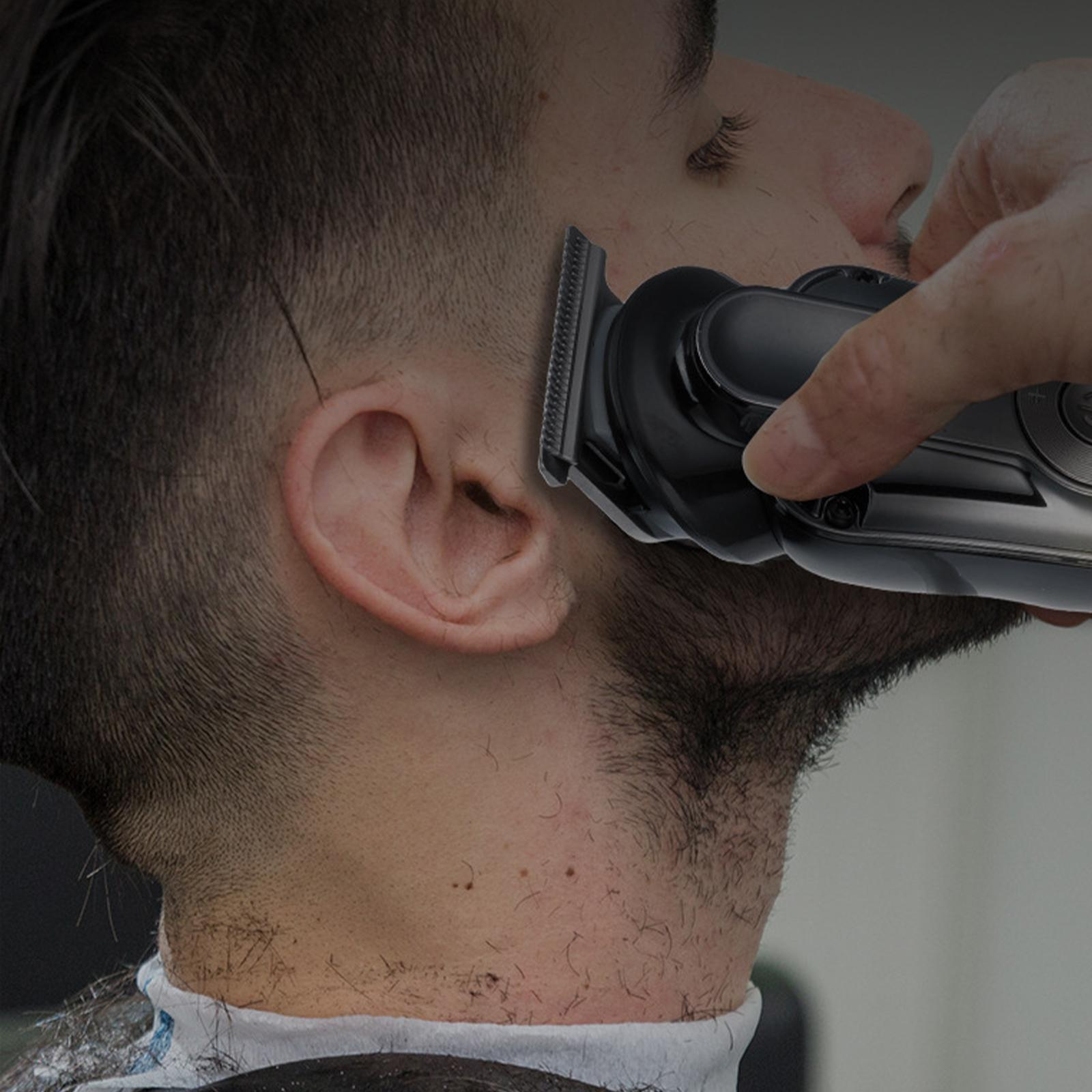 Das Gesicht eines Mannes, der sich den Bart schneiden lässt. Der Friseur benutzt einen elektrischen Trimmer.