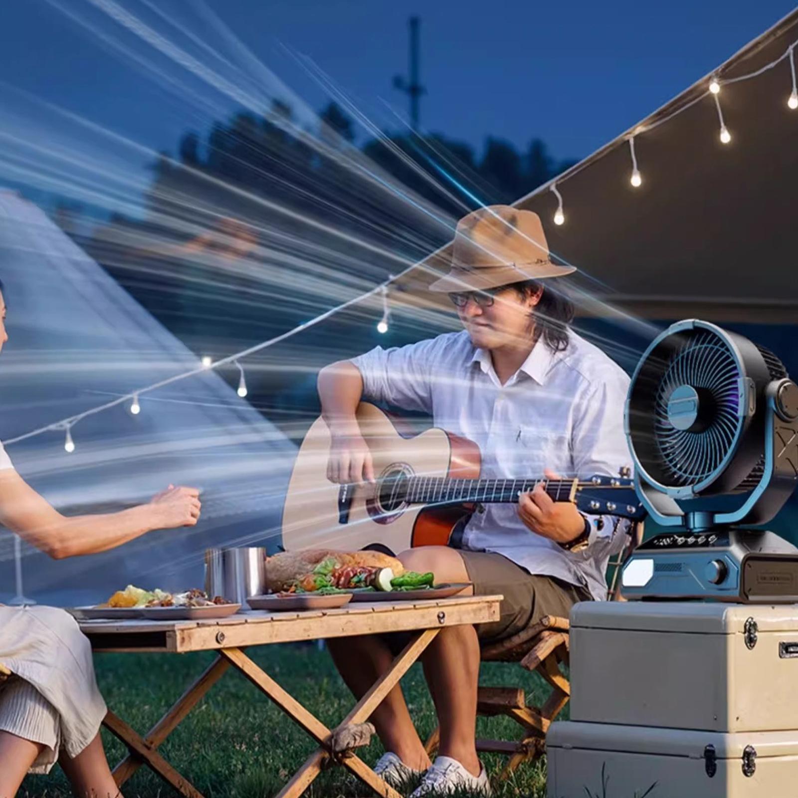 Menschen genießen Musik und Essen in der Nähe eines Campingventilators unter Lichterketten.