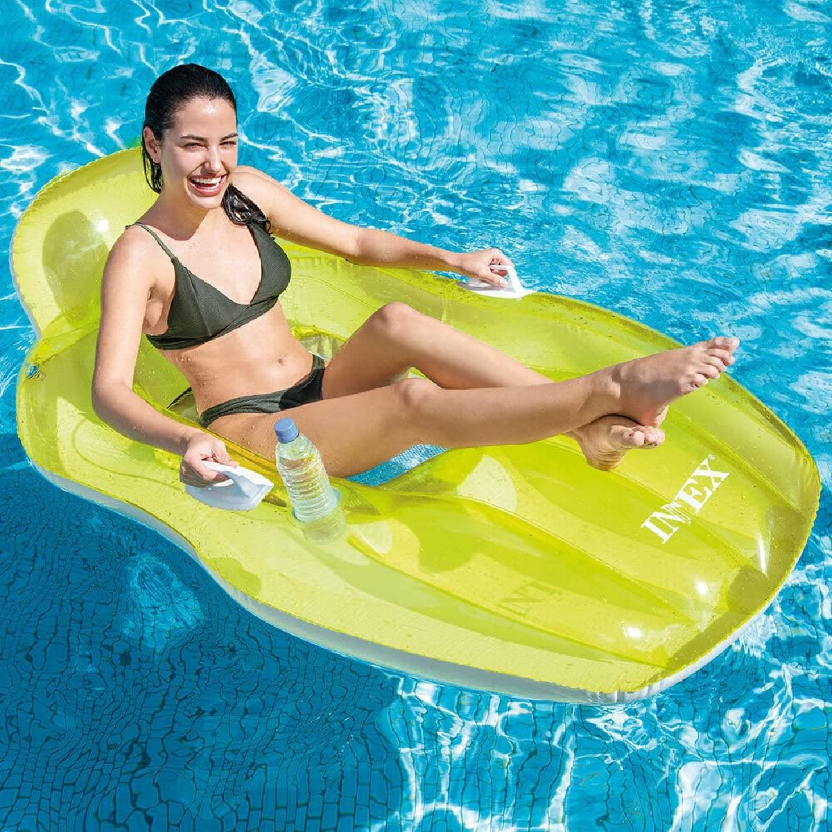Frau in einem Pool auf einem limettengrünen aufblasbaren Lounger mit einer Wasserflasche.
