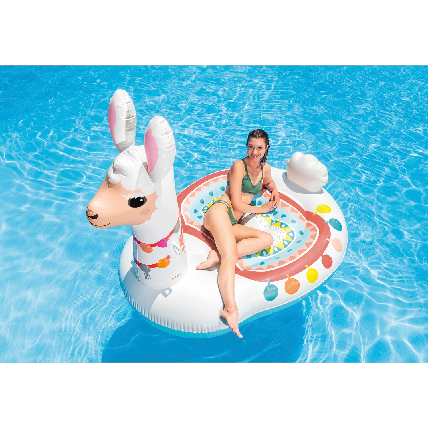Una donna galleggia su un gonfiabile a forma di lama in piscina. Indossa un top e un pantalone verdi.