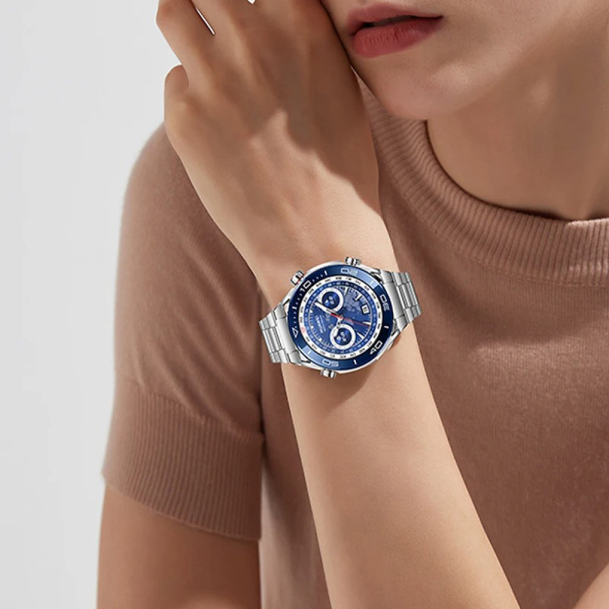 Am Handgelenk einer Frau ist eine blaue und silberne Uhr zu sehen. Die Uhr hat mehrere Zifferblätter.