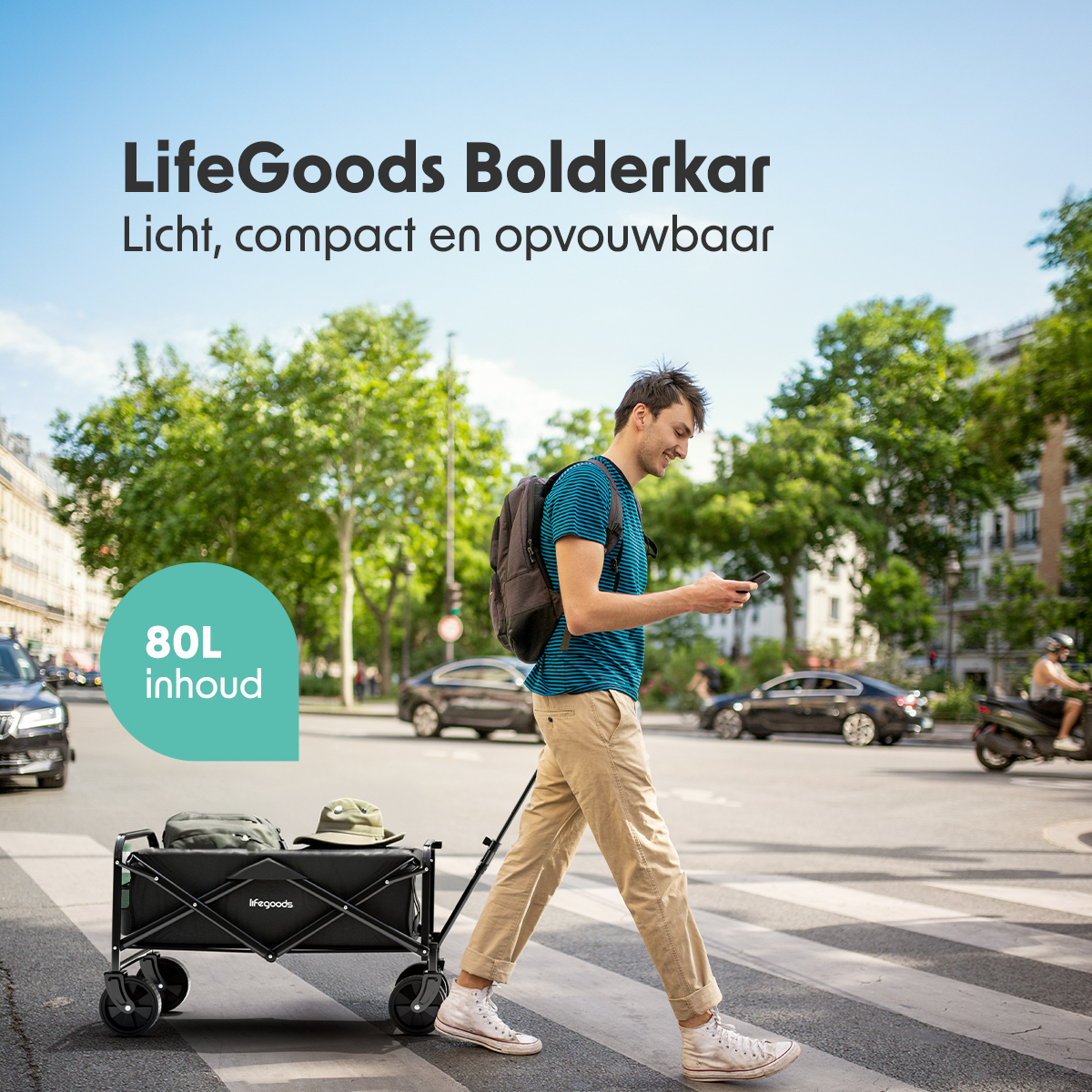 A man is walking with a LifeGoods wagon on a street. The background shows buildings and traffic.