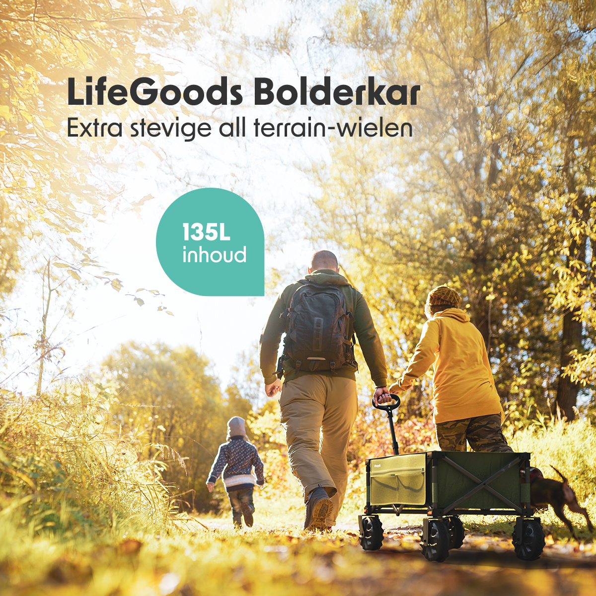 People walking with a black wagon in a sunny, wooded area. One child runs ahead.