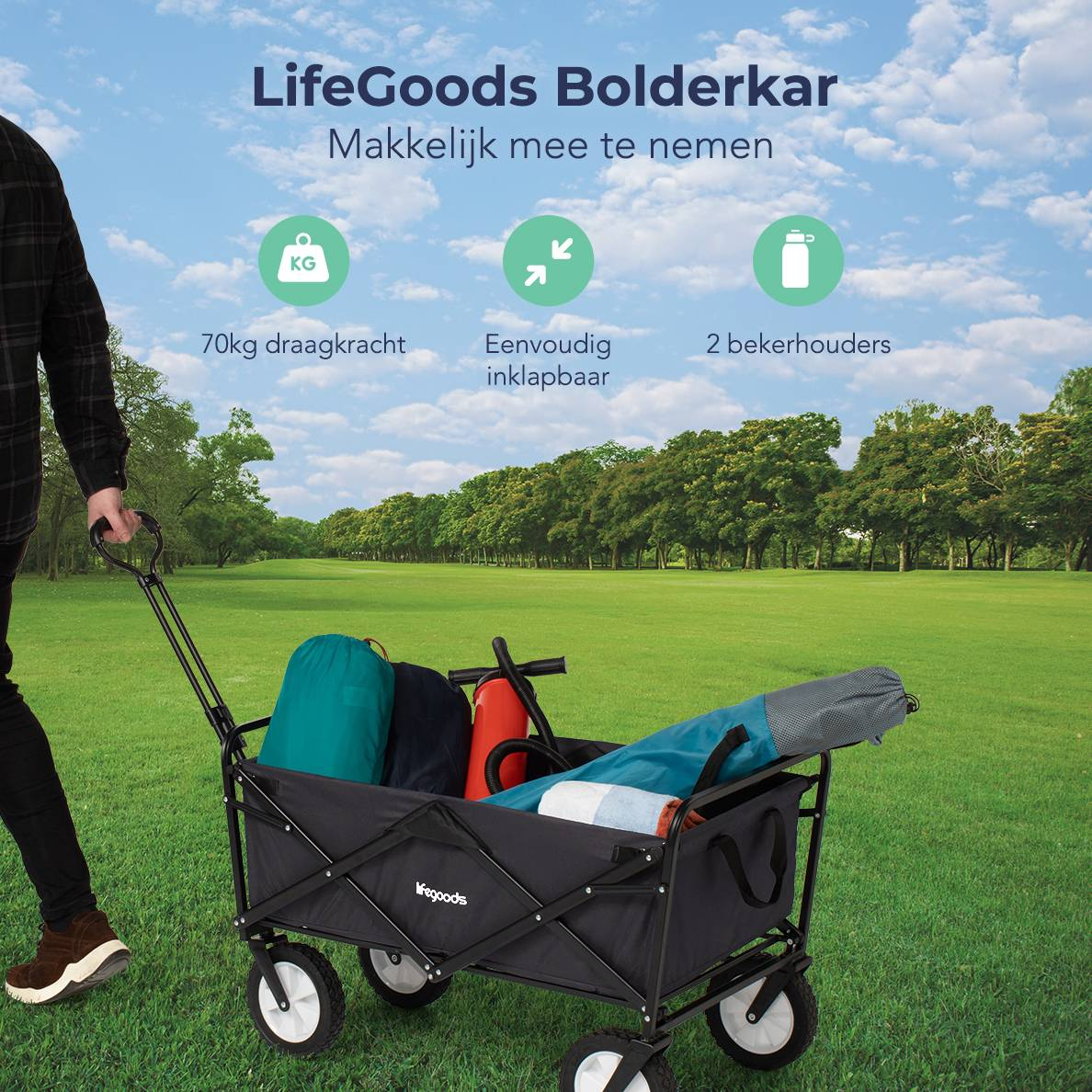 A man pulls a black cart with a blue sky background. The cart is loaded with items.