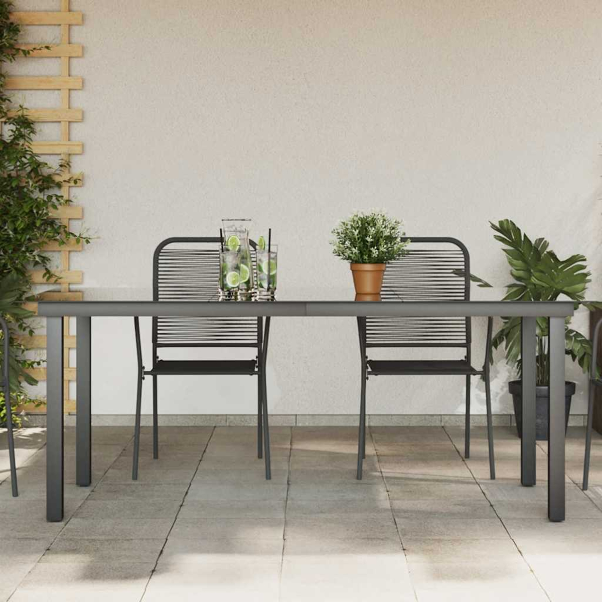 Szene im Freien mit Tisch, Stühlen, Getränken und Pflanzen auf einer Terrasse.