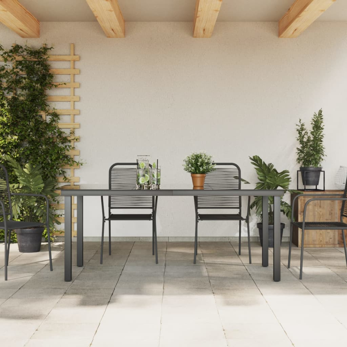 Eine Esszene im Freien mit Tisch, Stühlen, Pflanzen und einem Spalier. Die Umgebung ist terrassenähnlich.