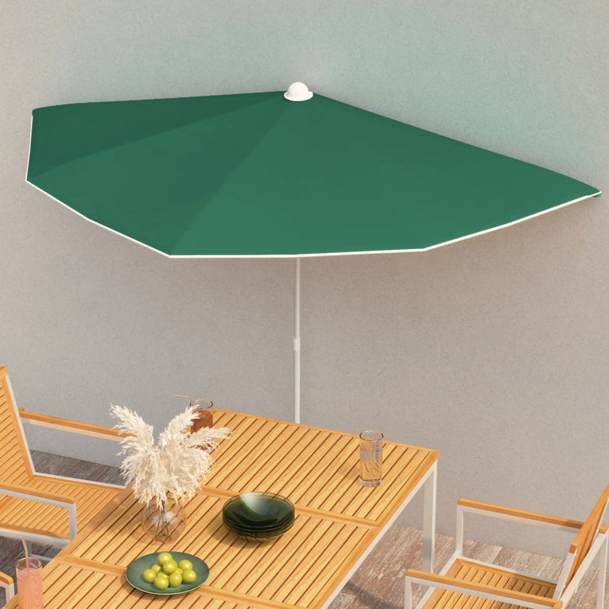Ein grüner Sonnenschirm über einem Tisch mit Essen und Getränken, in der Nähe einer Wand und Stühlen.