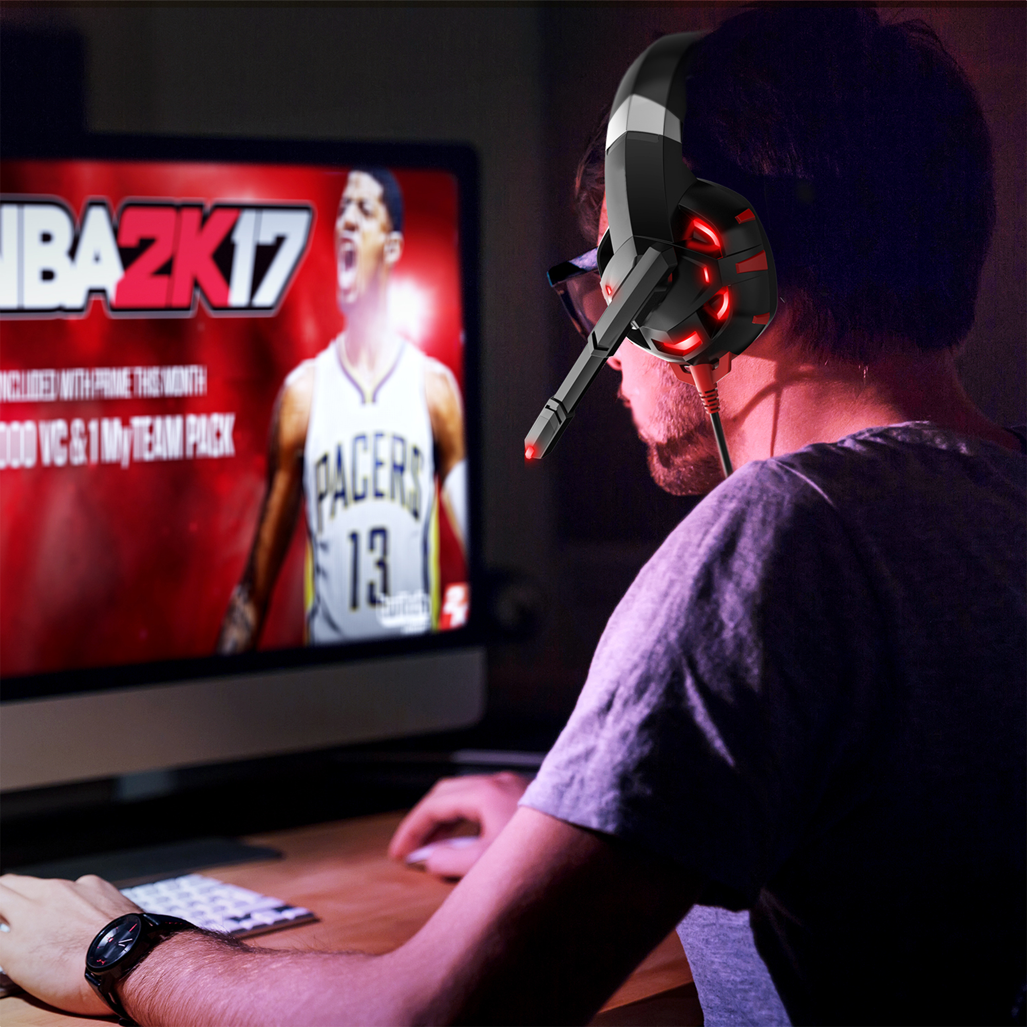 A man wearing a gaming headset looks at a computer screen showing a basketball game. He is using a mouse.