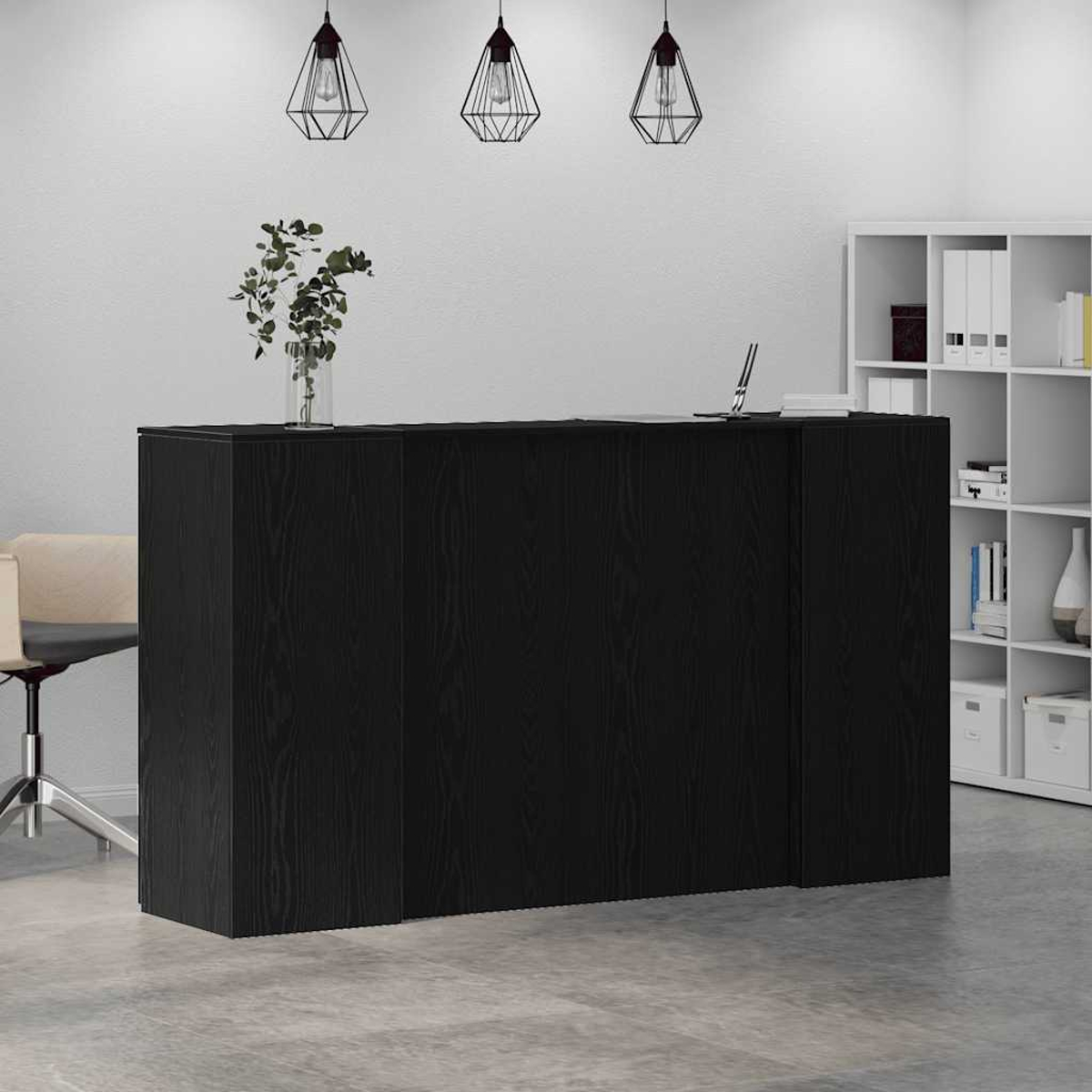 Ein schwarzer Schreibtisch mit einer Vase mit Pflanzen und einem Laptop darauf.