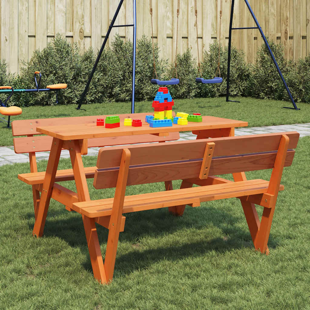 Picknicktisch mit Bänken, Holz orange, Spielzeug, Schaukel im Hintergrund.