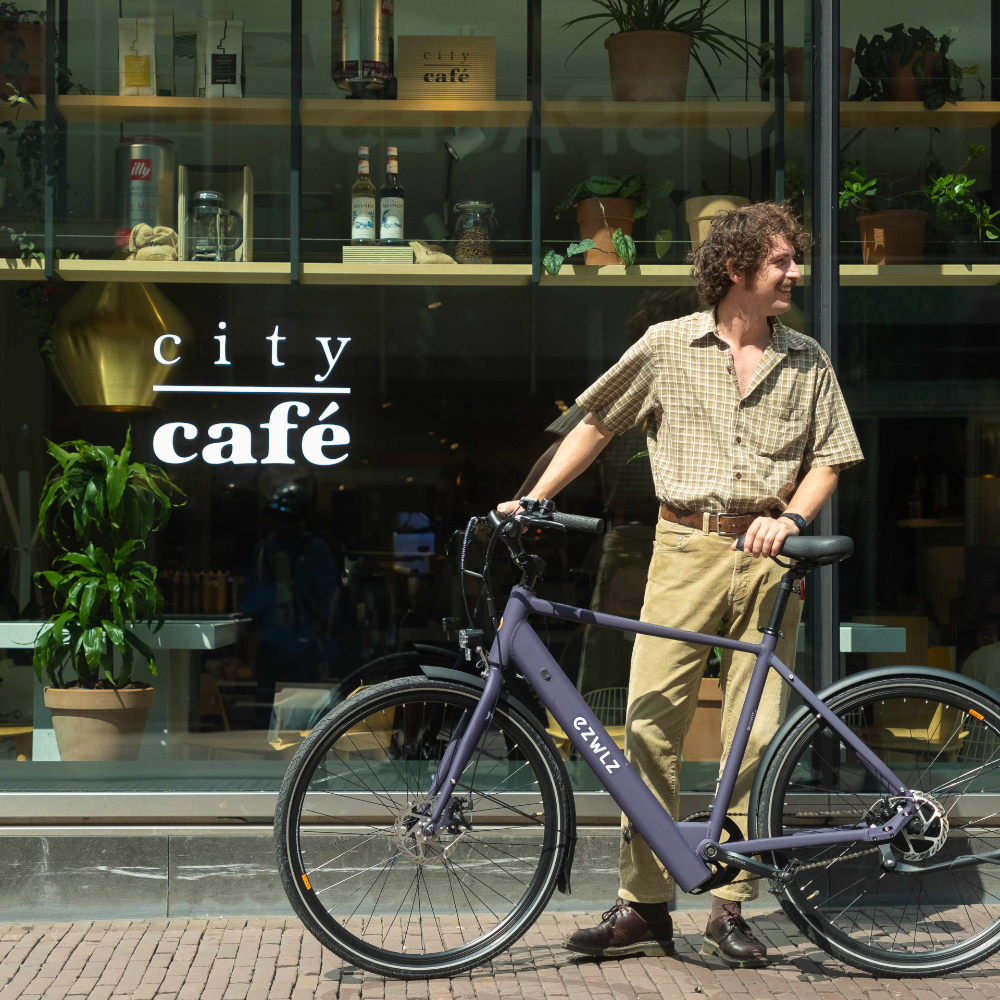 Man met fiets buiten café met bord.