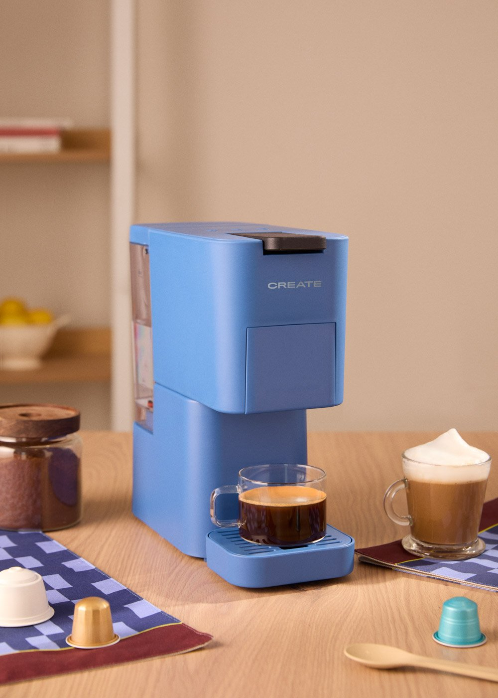 Una cafetera azul con una taza de café y otros accesorios.