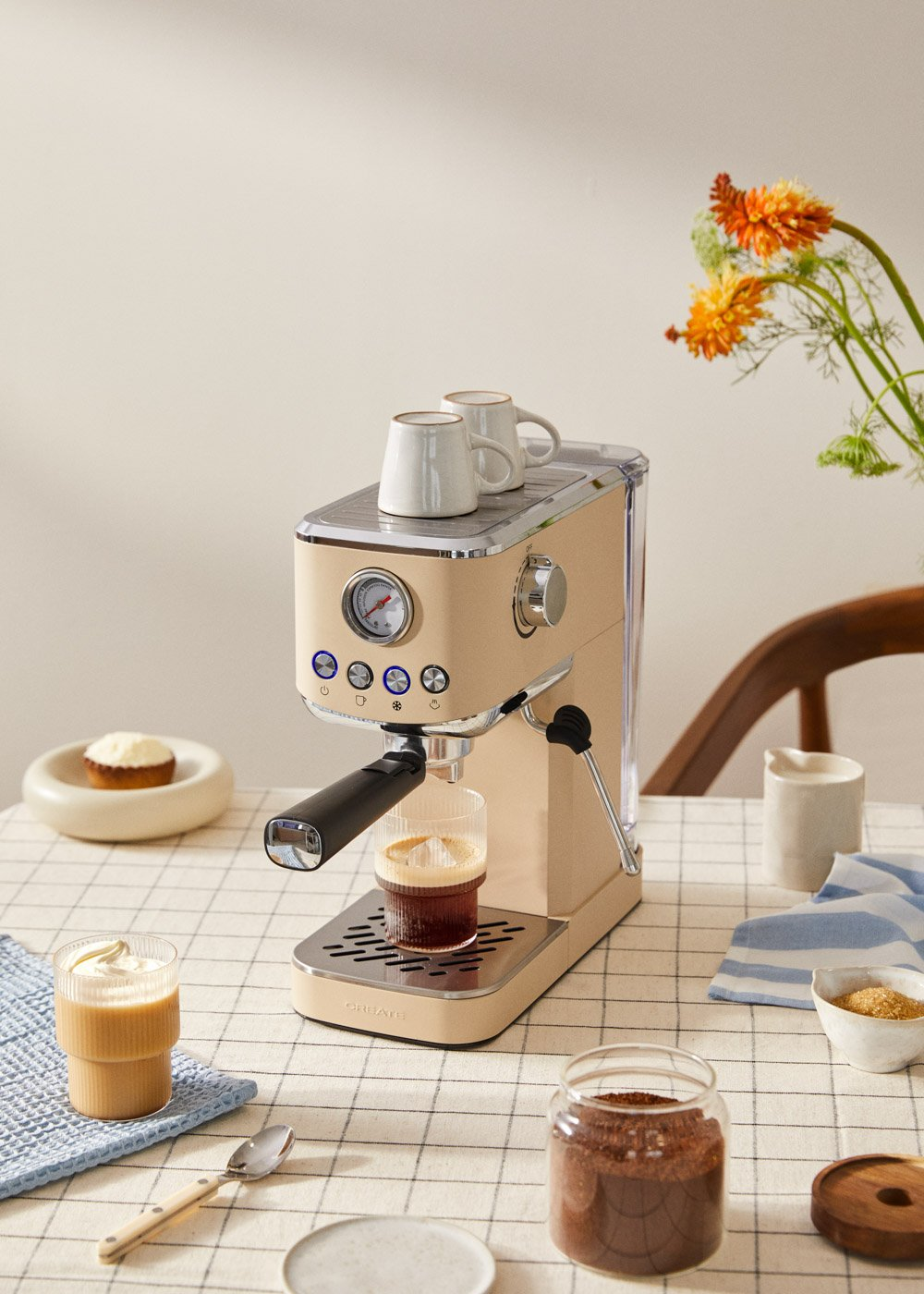Una máquina de espresso beige con una taza de café y otros accesorios.