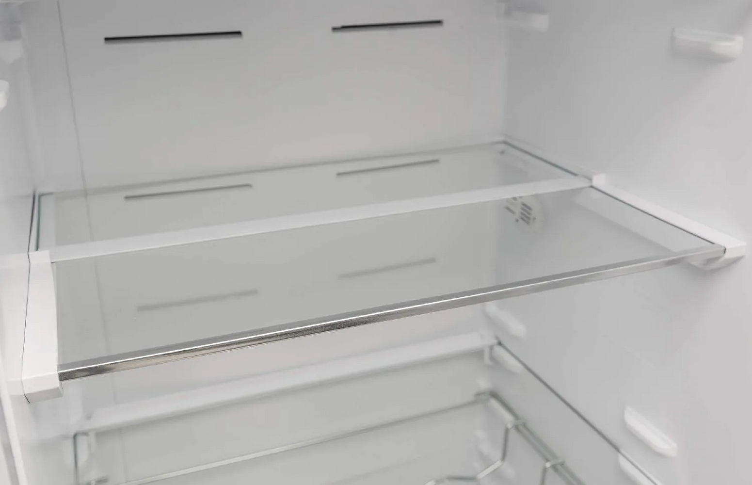 L'interno di un frigorifero con due ripiani in vetro. I ripiani hanno una finitura argentata.