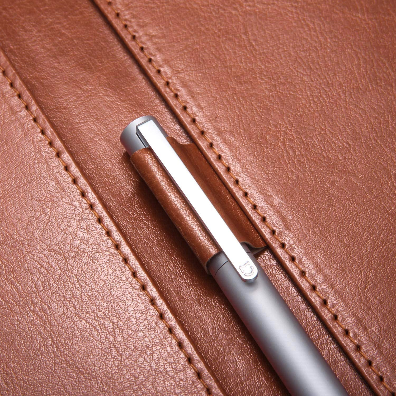 Nahaufnahme eines Stifts in einem braunen Leder-Notizbuch. Der Stift ist silberfarben mit braunem Ledergriff.