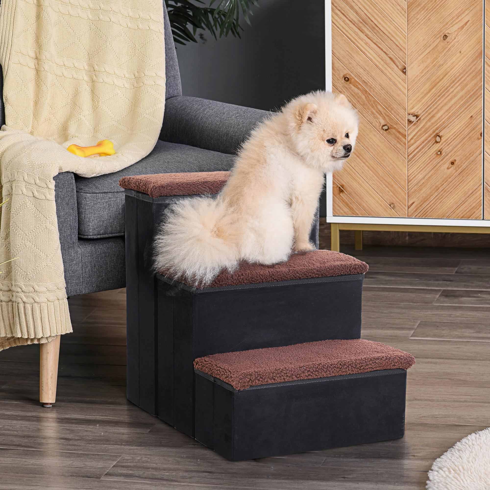 Ein kleiner Hund sitzt auf einer Haustiertreppe. Ein Stuhl, eine Decke und ein Schrank sind im Hintergrund.