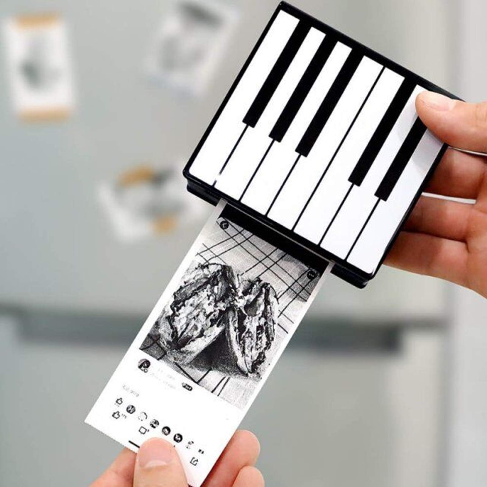 Eine Person druckt ein Foto aus einem kleinen, schwarz-weißen Drucker in Keyboard-Form.