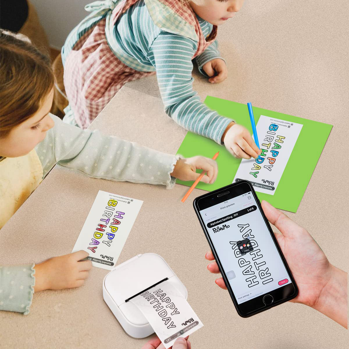 Zwei Kinder basteln Geburtstagskarten. Ein Drucker und ein Telefon mit Kartendesigns sind vorhanden.