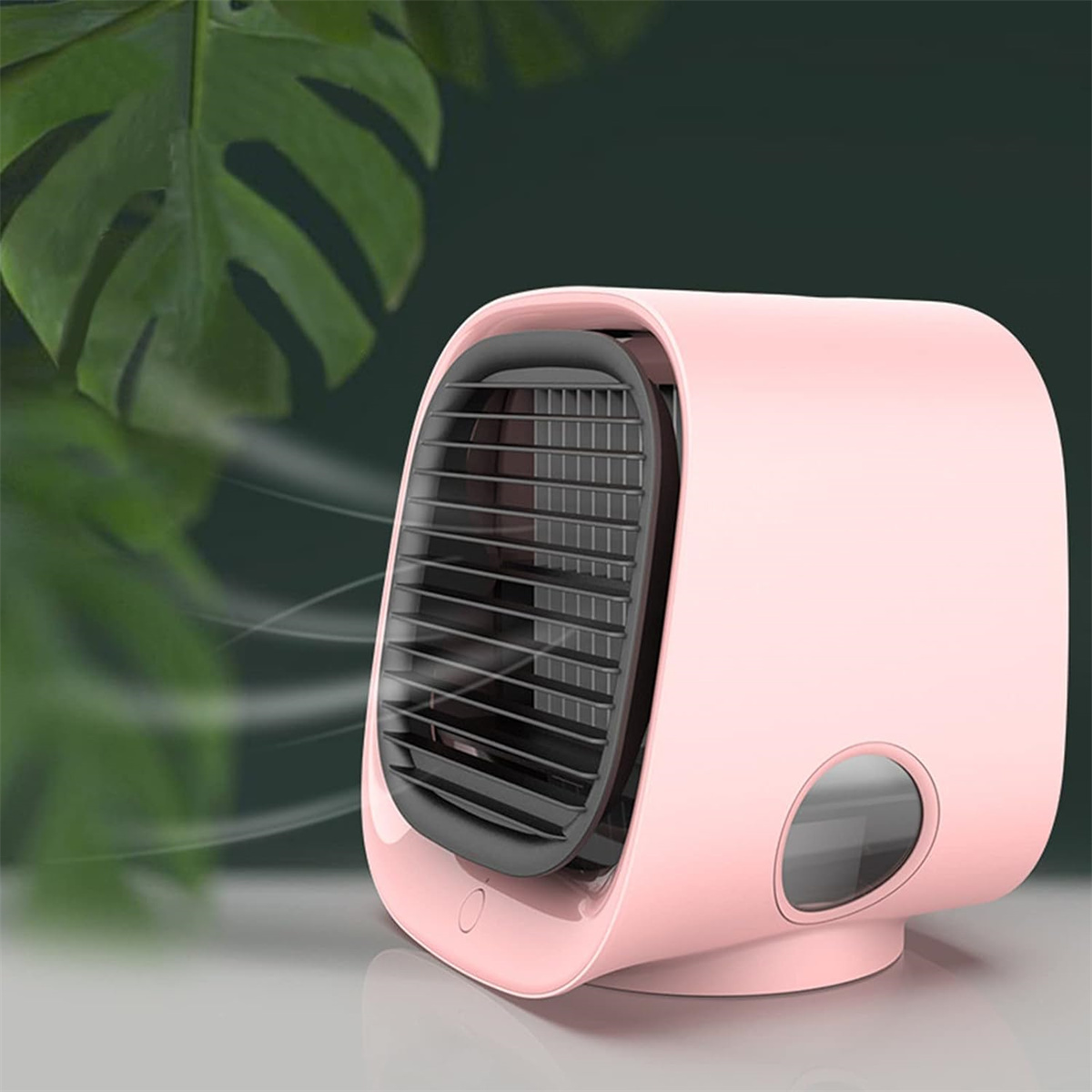 Ein rosa Mini-Ventilator auf einem Tisch. Er bläst Luft in Richtung des Betrachters. Im Hintergrund ist ein dunkles grünes Blatt.