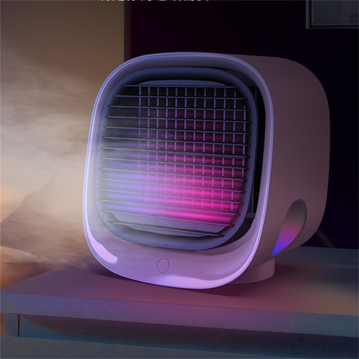 Ein weiß-rosa Mini-Ventilator auf einem Tisch, der Luft ausstößt. Der Ventilator hat einen blauen Power-Knopf. Es gibt einen dunklen Hintergrund.