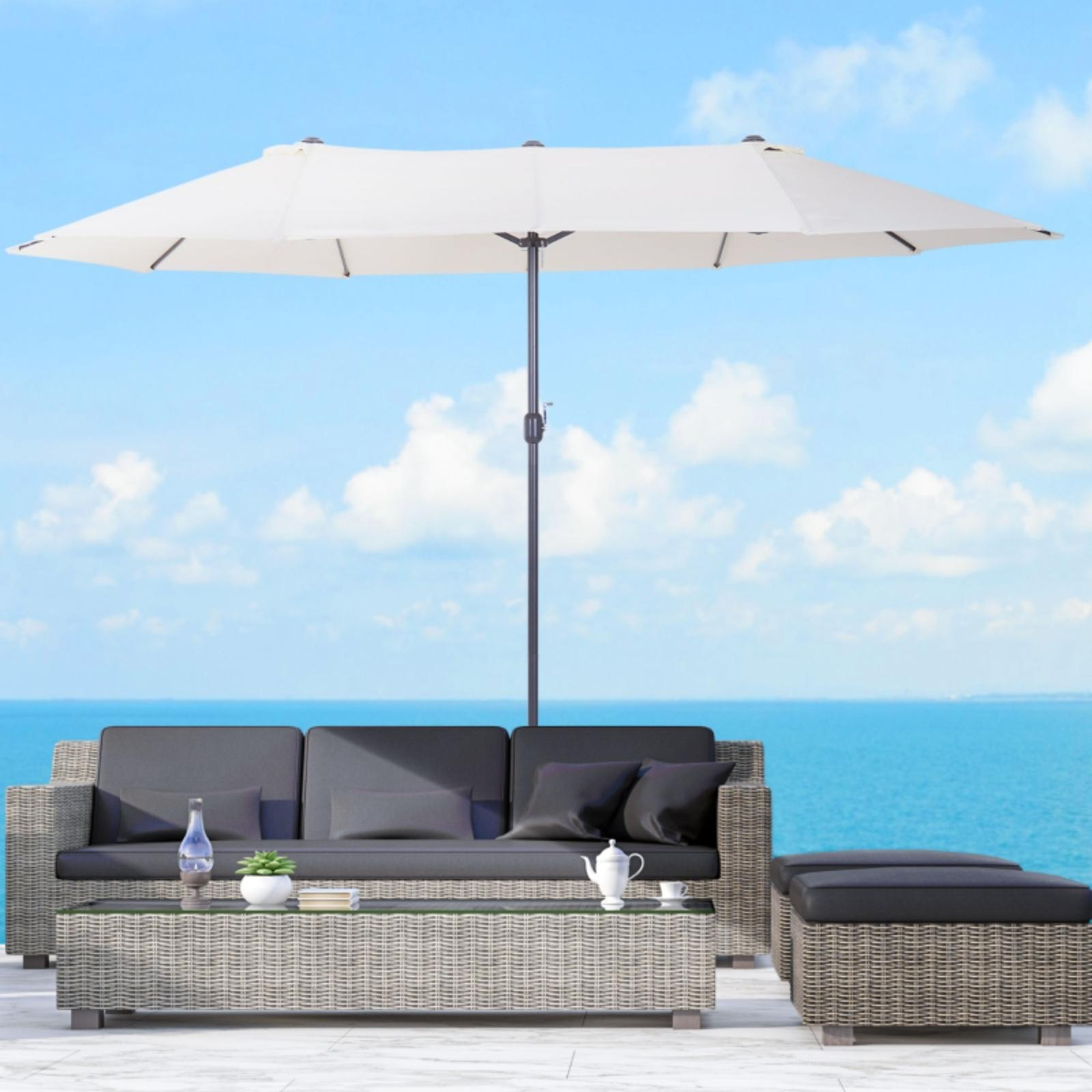 Szene im Freien mit einem weißen Schirm über einem grauen Korbmöbel-Sofa und einem Tisch mit Getränken.