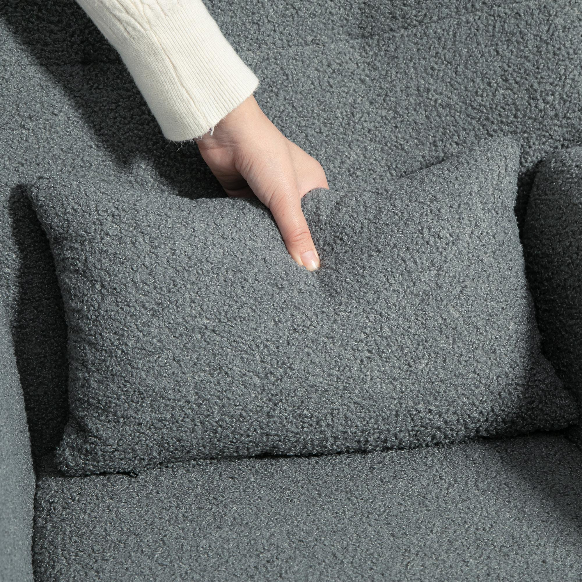 Hand platziert ein graues Kissen auf einem grauen Stuhl. Der Stuhl besteht aus einem flauschigen Material.