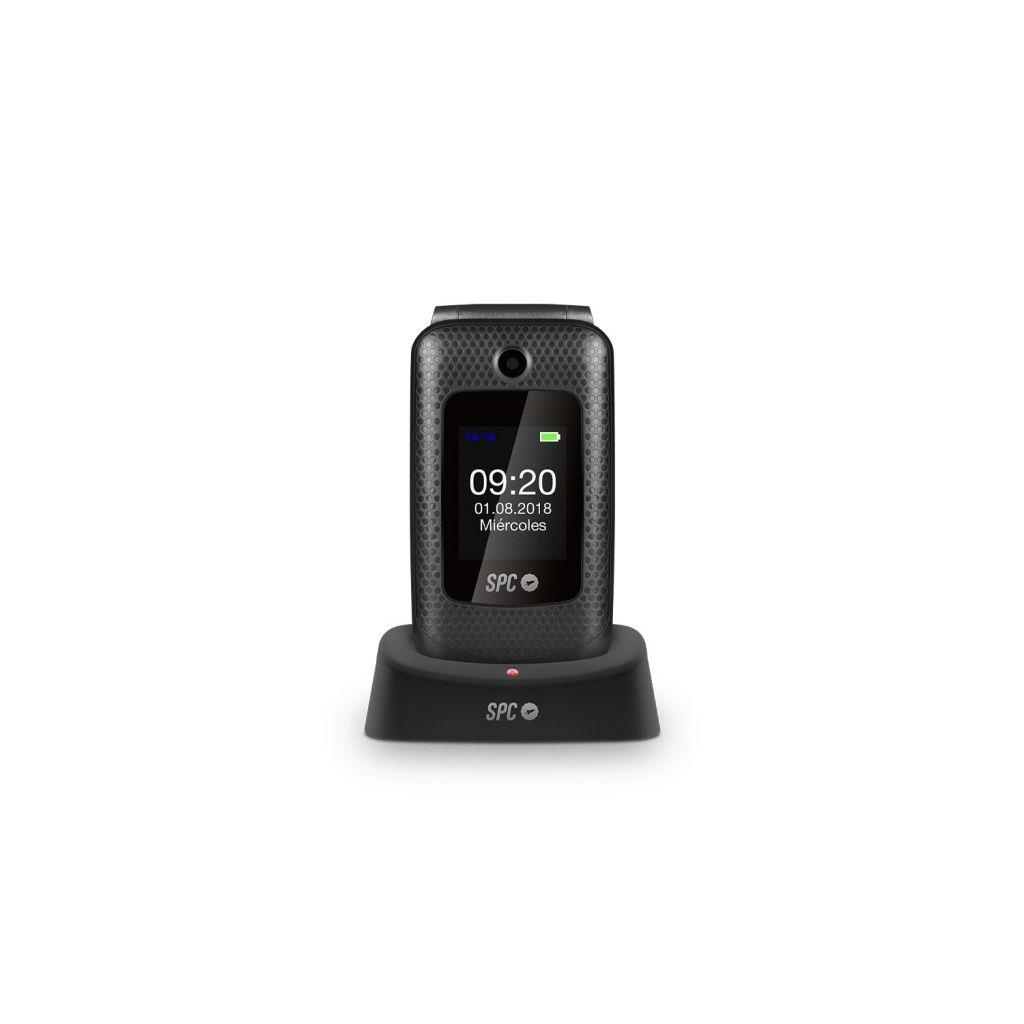 Se muestra un teléfono plegable SPC negro con fecha y hora en una base de carga.