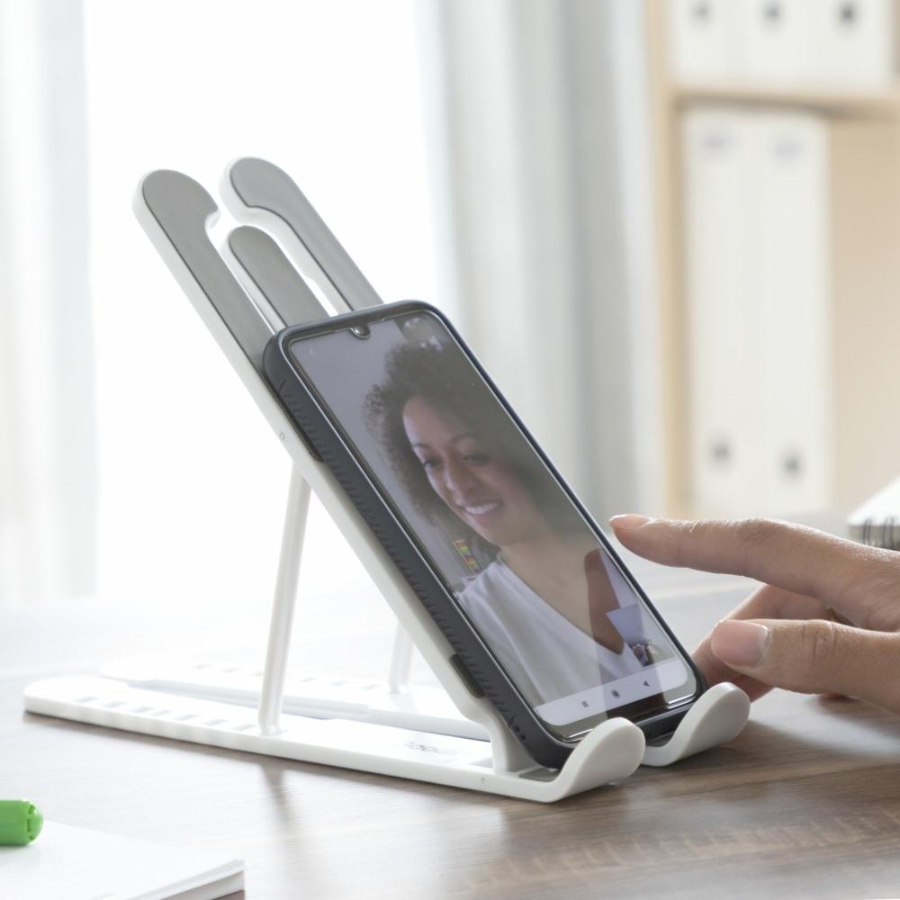 Un telefono in un supporto con una donna sullo schermo; mano che regola il telefono.
