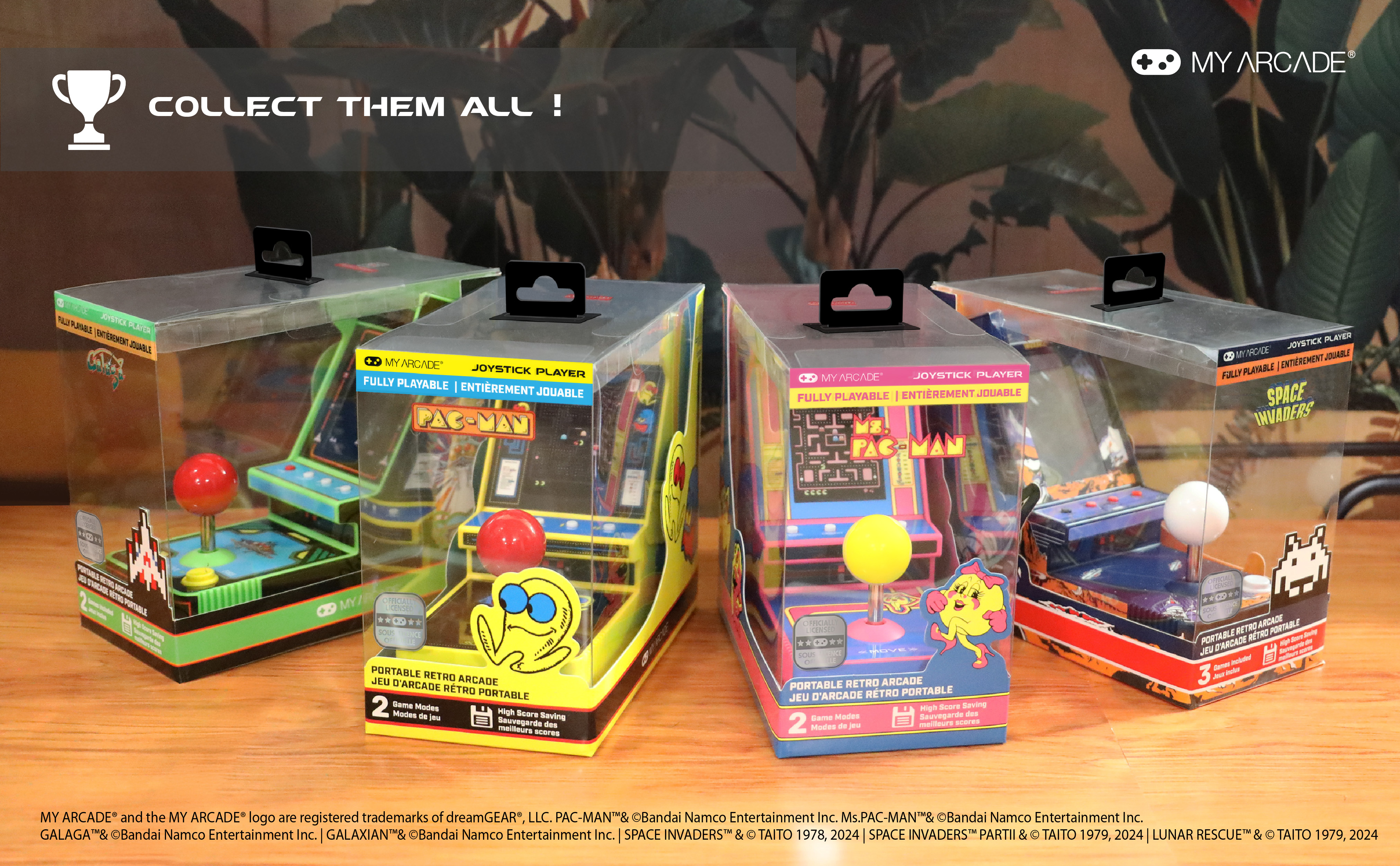 Mehrere Retro-Arcade-Spielboxen mit Pac-Man- und Space-Invaders-Branding sind gestapelt. Eine Trophäe ist sichtbar.